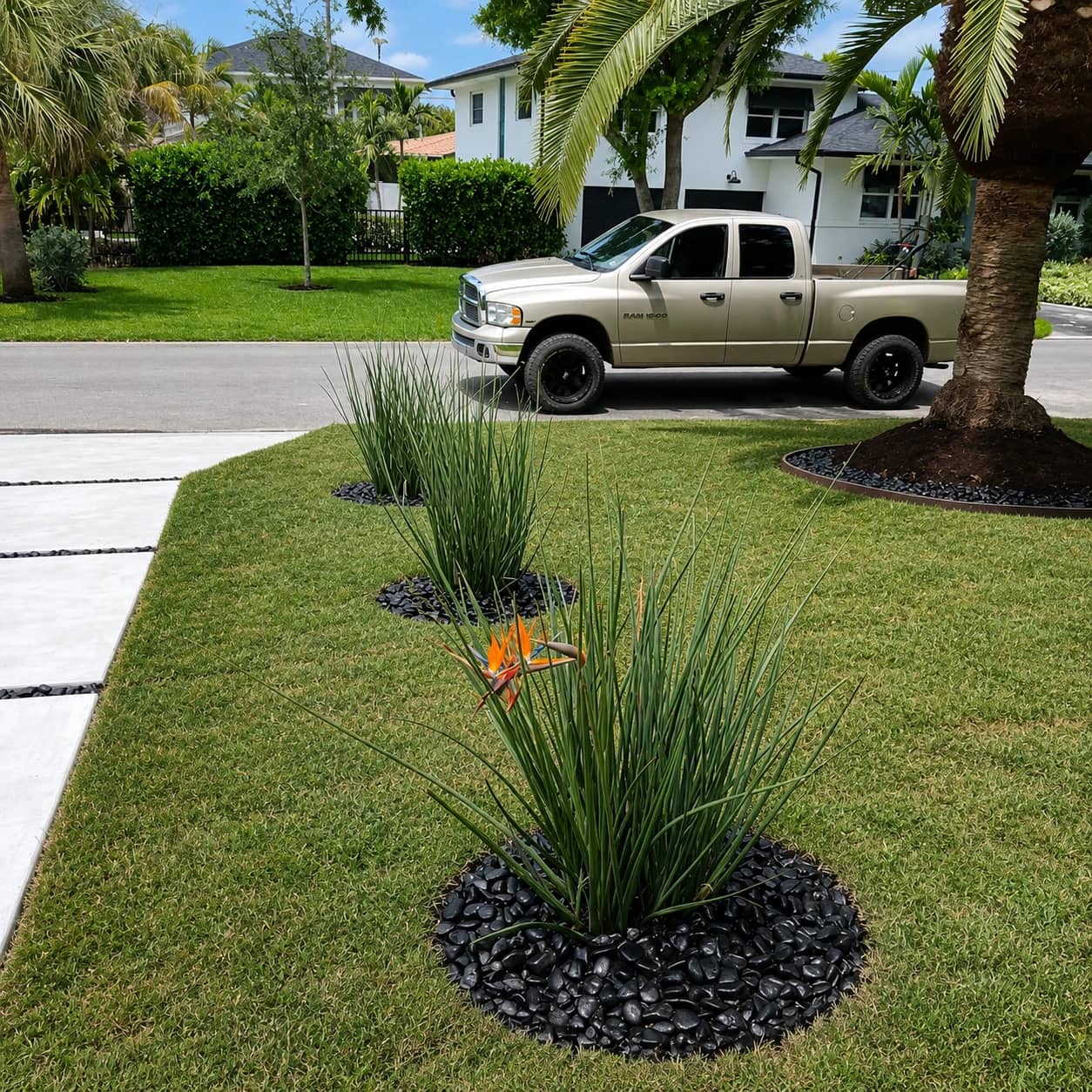 Finished hardscape project with pavers, landscape rock, and tropical plants around a home entry.