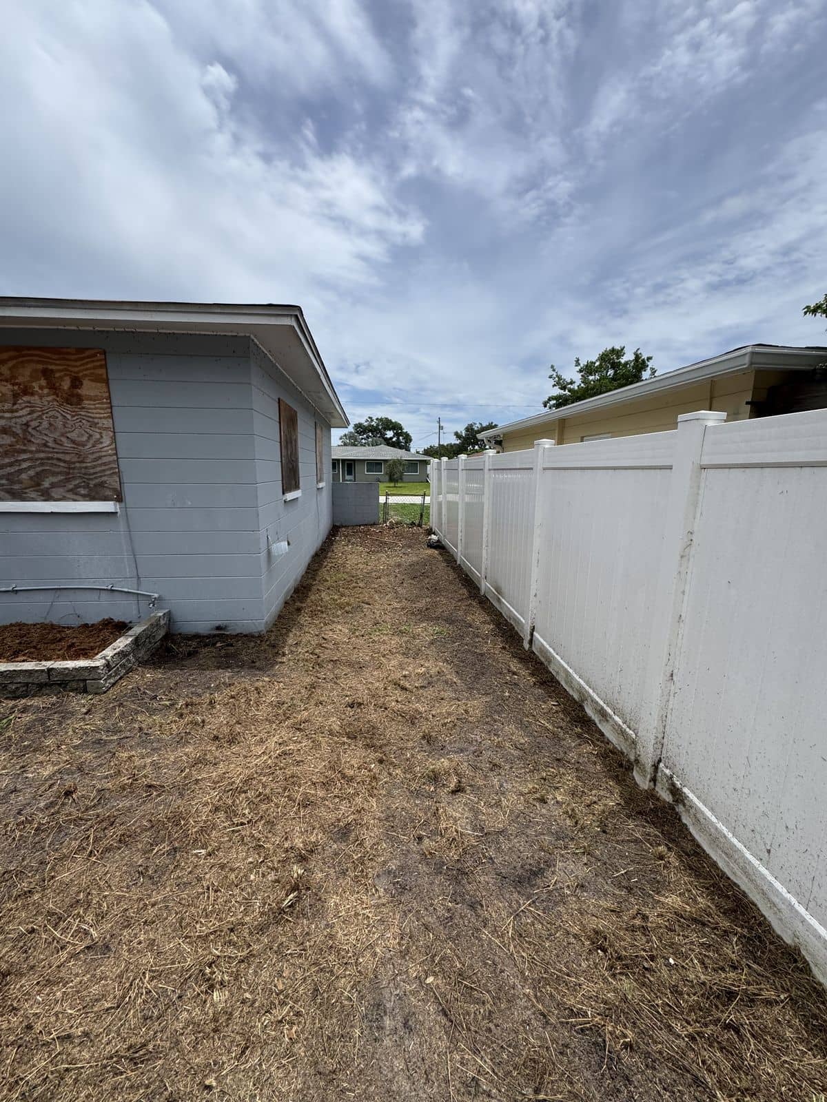 Side yard cleared and graded between the house and the fence, ready for new growth.