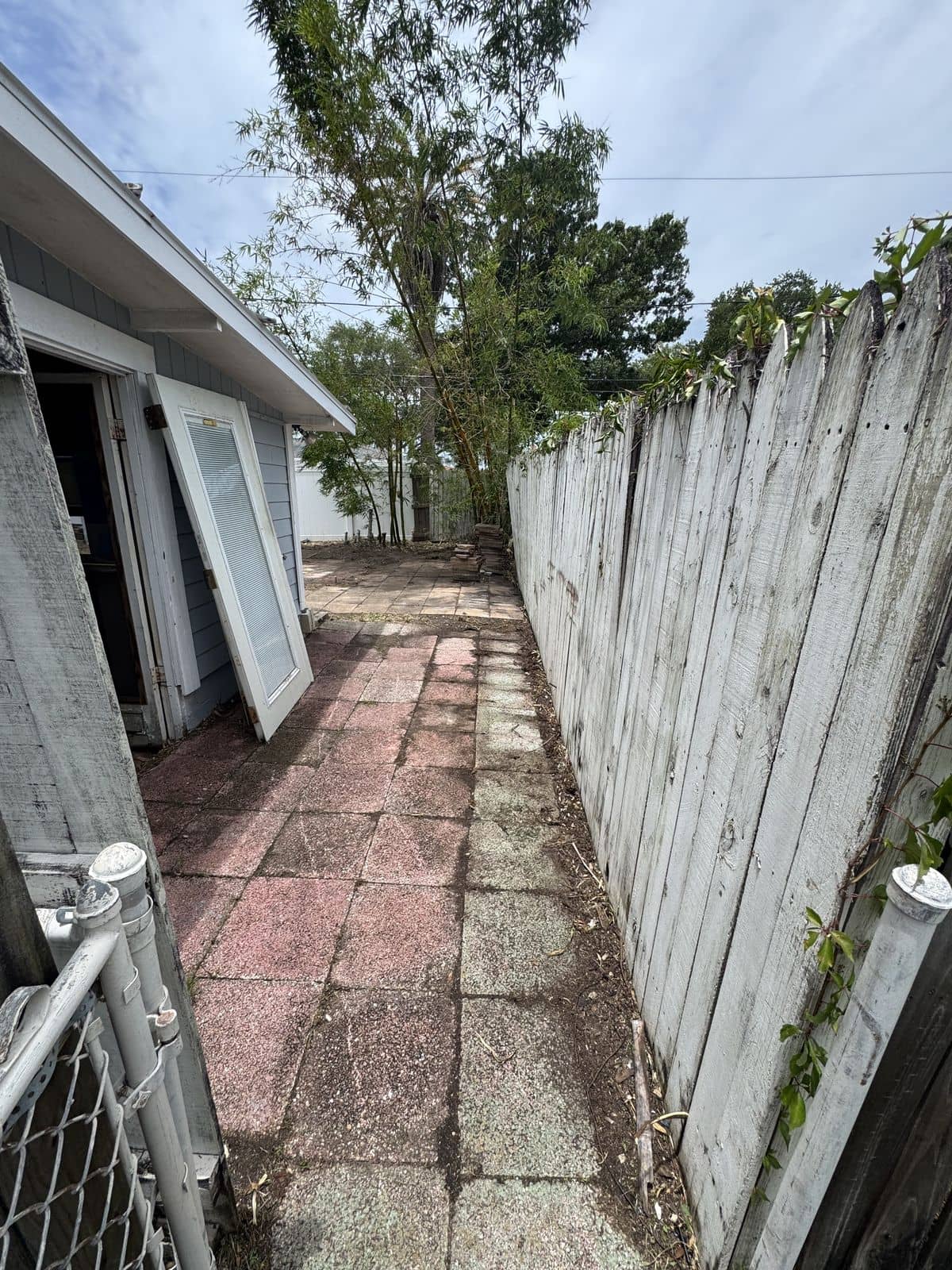 After photo of the same side yard with the vines cleared off the wall and the walkway opened back up.