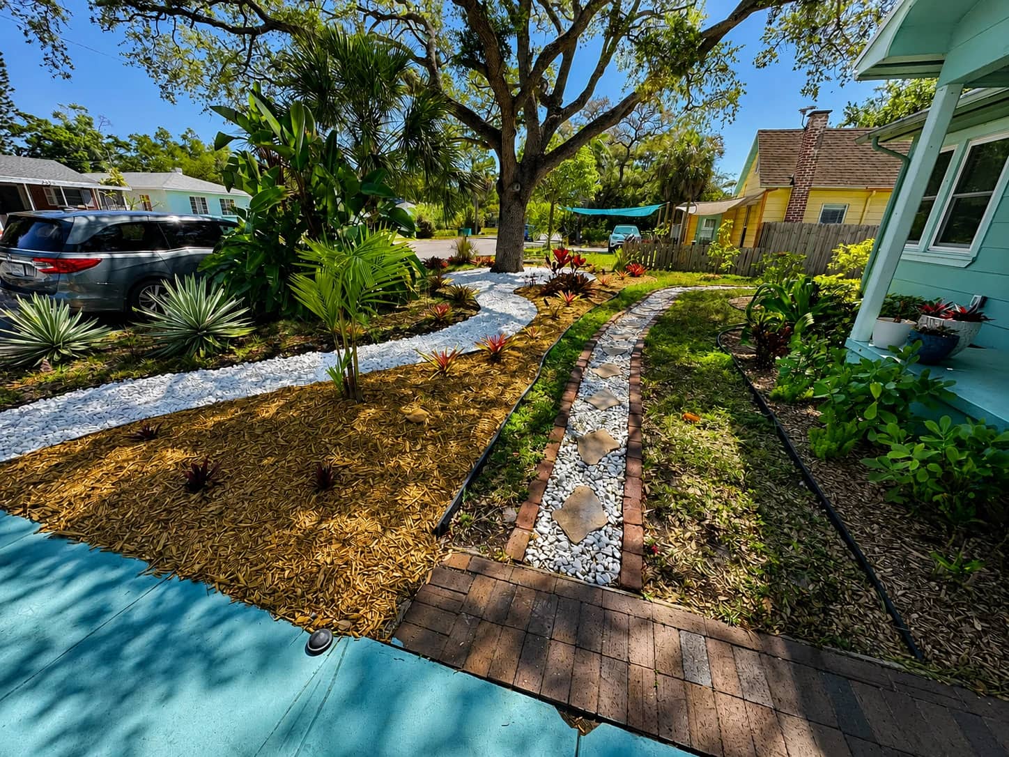 Finished Florida yard refresh with mulch, white rock, plants, and a bordered walkway.