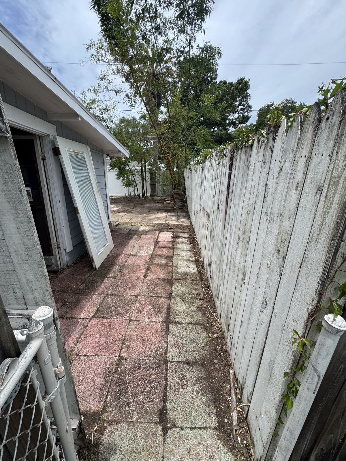 After photo of the same side yard with the vines cleared off the wall and the walkway opened back up.